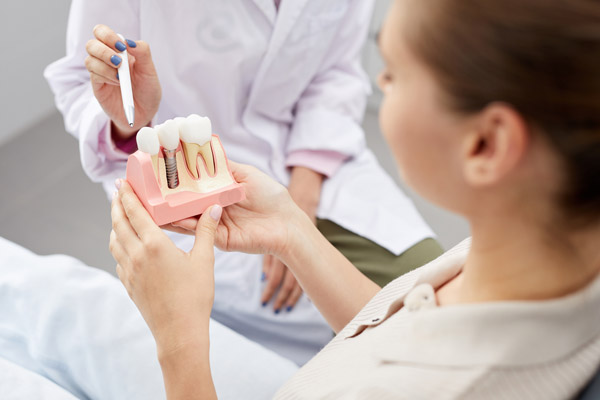 Image of a dental professional showing a patient that a dental implant is affordable and a good fit for her, at United Smile Centres.