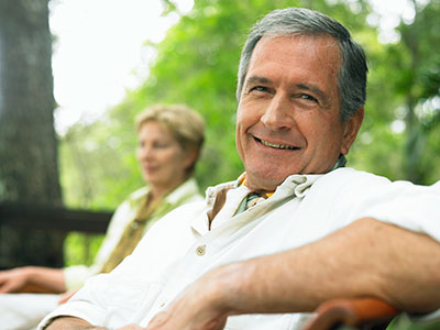 Elderly couple sitting in the bench at the greeny park.