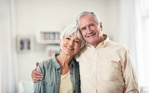 Elderly couple lean on each other and posing and smiling to camera