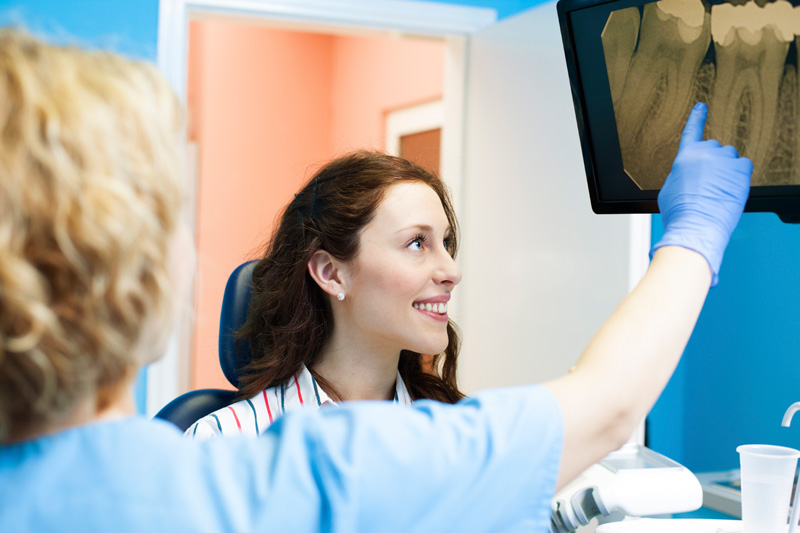 Doctor pointing out dental x-ray in the screen, explaining to patient at United Smile Centres, Louisville, KY