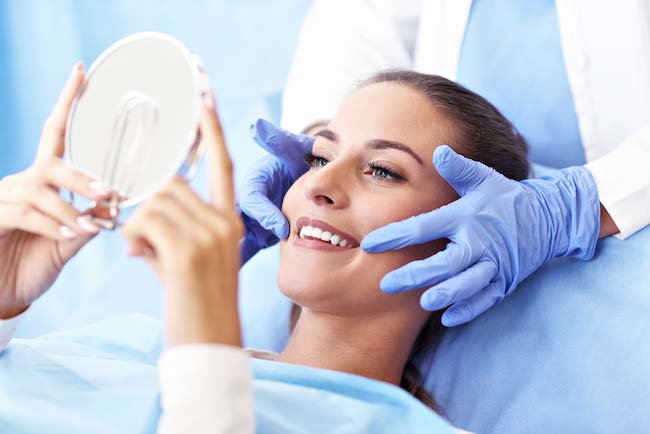 Image of a woman smiling, looking at the mirror.